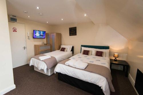 a bedroom with two beds and a tv on the wall at Snooze Apartments in Bradford