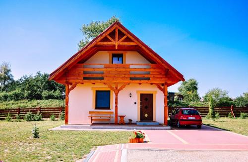 a small house with a red car parked in front of it at Żwirowa Góra - Domki nad Narwią in Tykocin
