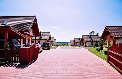 a red brick road with houses and a car on it at Żwirowa Góra - Domki nad Narwią in Tykocin