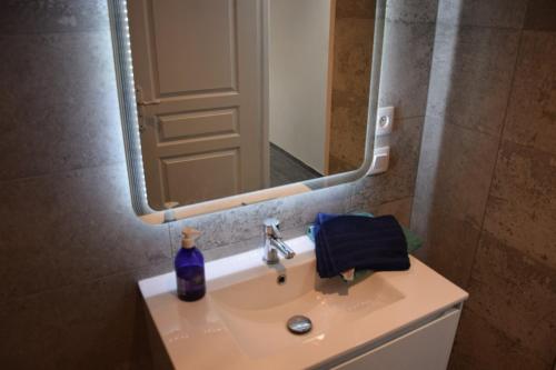 a bathroom sink with a mirror and a blue bottle on it at L'orée du Saint Quentin in Lessy