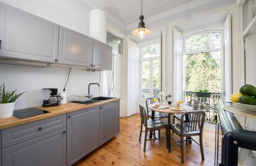 a kitchen with white cabinets and a table with chairs at Lisbon Dreams Estrela TOP Suites in Lisbon