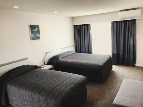 a hotel room with two beds and a window at The Village Inn Hotel in Te Anau
