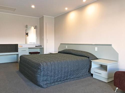 a bedroom with a large bed and a desk at The Village Inn Hotel in Te Anau