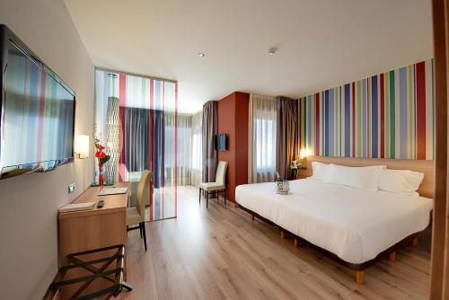 a hotel room with a bed and a desk and a television at Maisonnave in Pamplona