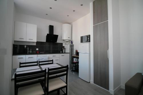 une cuisine avec des armoires blanches et une table et des chaises dans l'établissement Comme à la Maison - CENTRE-VILLE, à Saint-Quentin