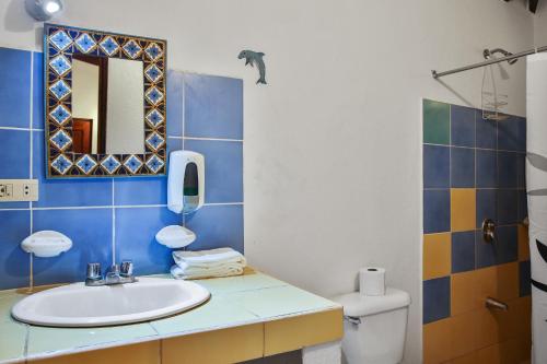 y baño con lavabo, espejo y aseo. en Villas Macondo en Tamarindo