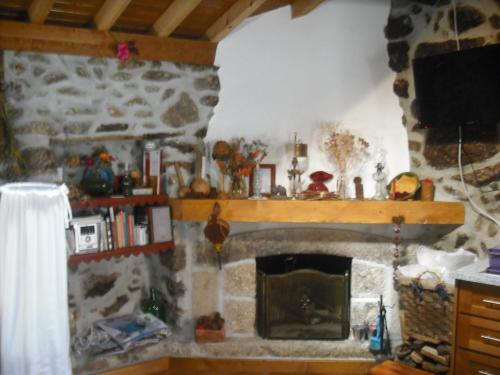 a living room with a stone fireplace with a television at Casa do Beirado in Gouveia