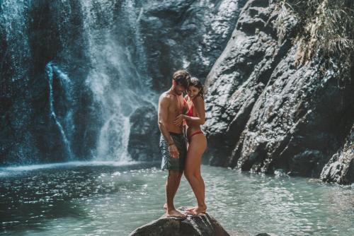 a man and a woman standing on a rock in front of a waterfall at Savasi Island Resort in Savusavu