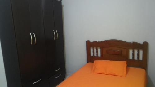 a bedroom with a bed with an orange pillow and black cabinets at Nossa Casa in Cunha