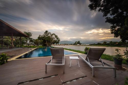 two chairs sitting on a deck next to a swimming pool at Doi Inthanon Riverside resort in Chom Thong
