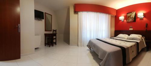 a bedroom with a bed and a red wall at Hotel Ria Toxa in Revolta