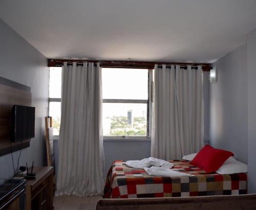 a bedroom with a bed and a large window at Apartamento confortável in Goiânia