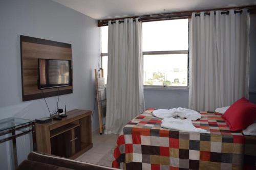 a hotel room with a bed and a television at Apartamento confortável in Goiânia