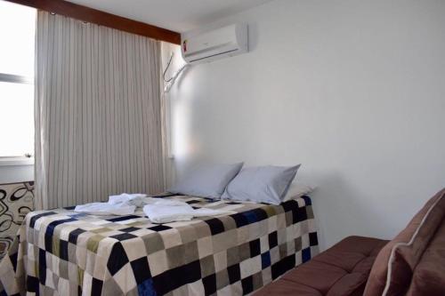 a bed with a checkered blanket in a room at Apartamento confortável in Goiânia