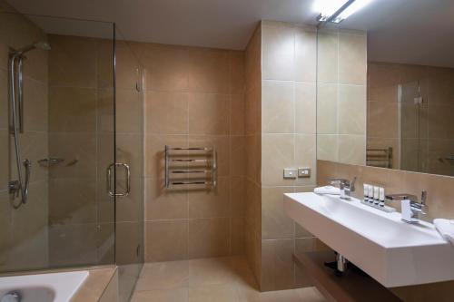 a bathroom with a shower and a sink and a mirror at Highview Apartments in Queenstown