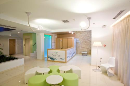 a hospital lobby with green tables and white chairs at Nefeli Apartments in Leptokaria