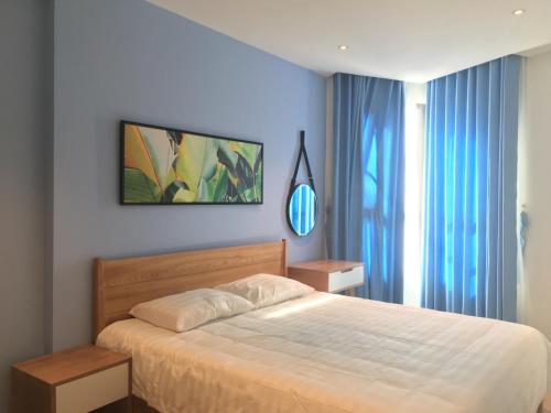 a bedroom with a large bed with blue curtains at Angela House Halong in Ha Long