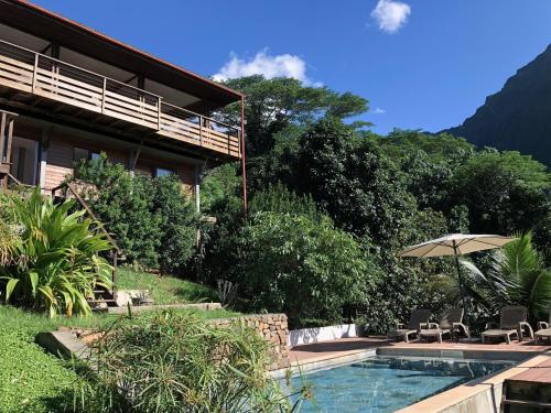 a house with a swimming pool and an umbrella at La Villa Te Fetia Nui Moorea in Teavaro