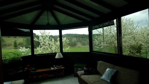 a living room with large windows and a couch at Chez Louis chambres d'hôtes à la ferme in La Canourgue