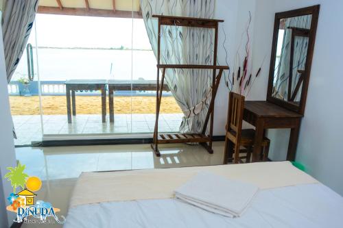 a bedroom with a bed and a large window at Dinuda Resort in Kalpitiya