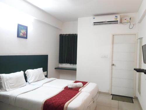 a bedroom with a large white bed and a window at SAP Golden Grande Electronic City in Bengaluru