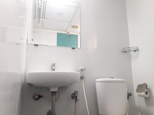 a white bathroom with a sink and a toilet at SAP Golden Grande Electronic City in Bangalore
