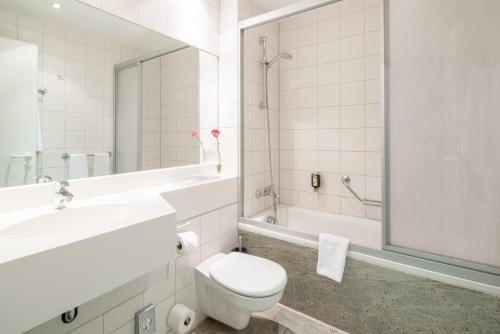 a bathroom with a toilet and a sink and a tub at Best Western Plus Hotel Excelsior in Erfurt