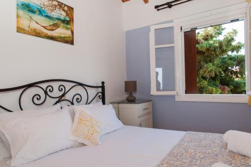 a bedroom with a white bed and a window at Villa Tettix (Τέττιξ) in Fiskardo