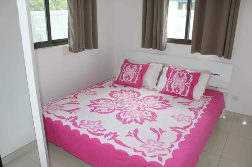 a bedroom with a pink and white bed with pink pillows at Bora-Bora House in Bora Bora