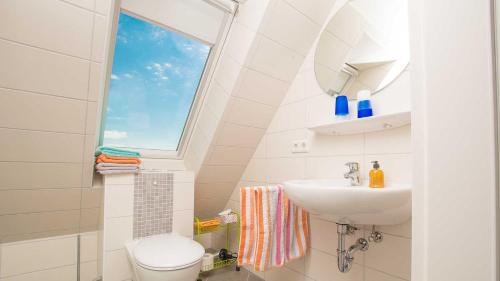 a bathroom with a sink and a toilet and a window at Herta Kruse Ferienwohnungen in Jork