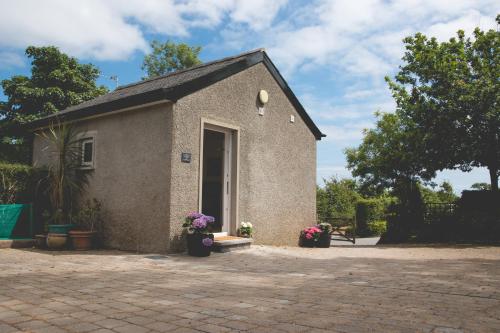a small building with flowers in a courtyard at The Stables at Ballygraffan in Comber