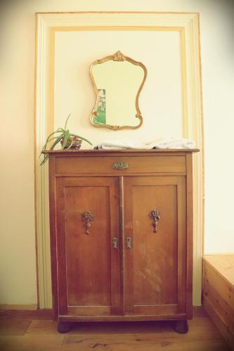 a wooden cabinet with a mirror on a wall at Spirit Lodge Leipzig in Leipzig