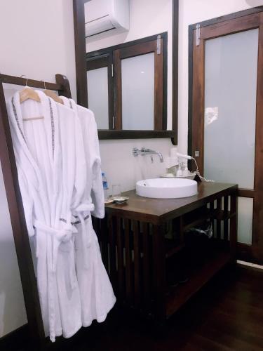 a bathroom with a sink and a white robe at Ancient Luangprabang Hotel in Luang Prabang