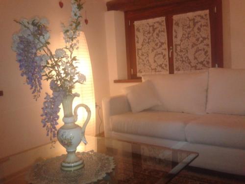a living room with a white couch and a vase with flowers at Alloggio Agrituristico Conte Ottelio in Pradamano