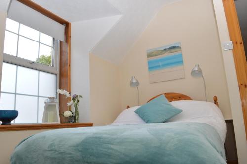 a bedroom with a bed and two windows at Flat 14c Bayhead in Stornoway