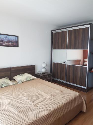 Un dormitorio con una cama grande y un gran armario de madera. en Tatyana Apartment en Burgas