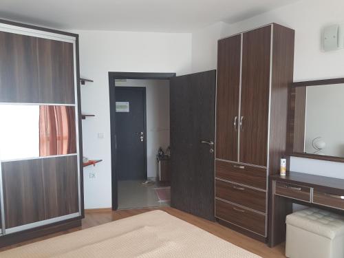 a bathroom with wooden cabinets and a door with a mirror at Tatyana Apartment in Burgas City