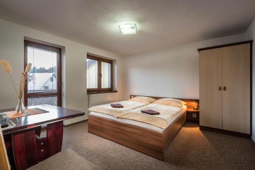 Schlafzimmer mit einem Bett, einem Schreibtisch und einem Fenster in der Unterkunft Penzion Goral in Terchová