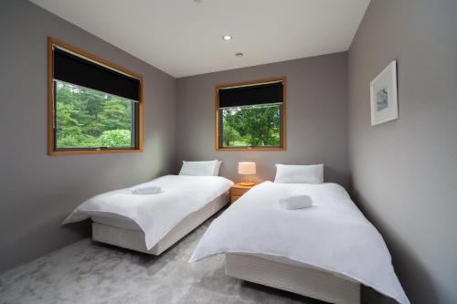 two beds in a room with two windows at Wagaya Chalet by Hakuba Hospitality Group in Hakuba