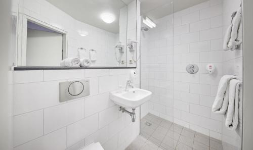 a white bathroom with a sink and a mirror at Singel Hotel Amsterdam in Amsterdam