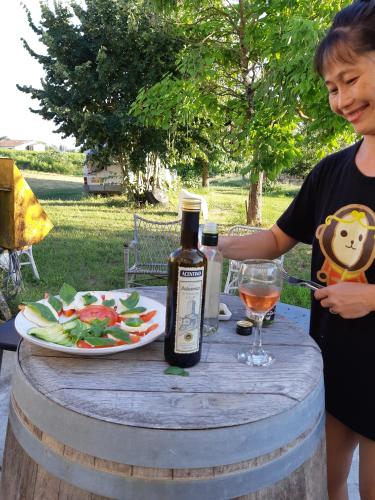 une femme assise à une table avec une bouteille de vin et une assiette de nourriture dans l'établissement Au Vélo dans l'Arbre, à Saint-Sulpice-de-Faleyrens