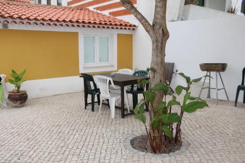 a patio with a table and chairs and a tree at A Casinha in Caldas da Rainha