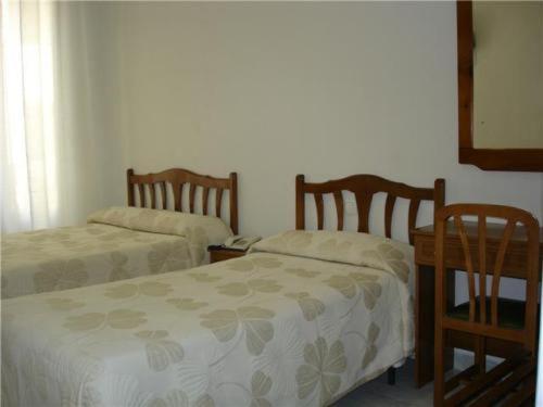 1 dormitorio con 2 camas, mesa y 2 sillas en Hostal Excelsior, en Madrid