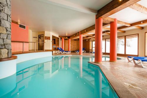 - une piscine dans un hôtel avec des chaises et des tables dans l'établissement travelski home select - Résidence L'Arollaie, à Peisey-Nancroix