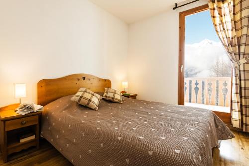 a bedroom with a bed and a large window at travelski home select - Résidence L'Arollaie 4 stars in Peisey-Nancroix