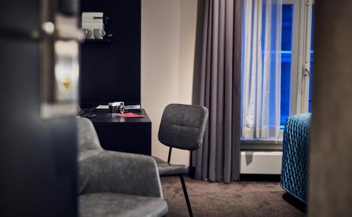 a room with a chair and a desk and a window at Singel Hotel Amsterdam in Amsterdam