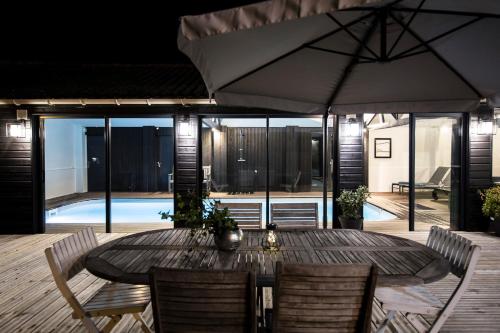 a wooden table with chairs and an umbrella on a patio at La Villa in Mesnil-Val-Plage