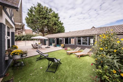 einen Hinterhof mit Stühlen und eine Terrasse mit Terrasse in der Unterkunft La Villa in Mesnil-Val-Plage