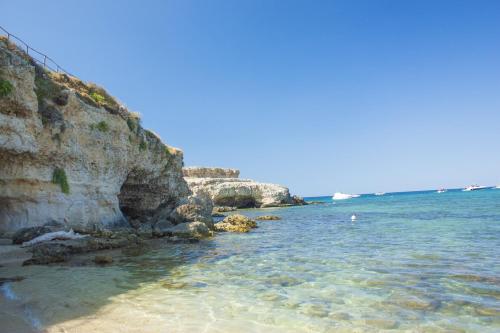 a beach with rocks and the water at Corvino Resort in Monopoli