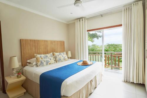 ein Schlafzimmer mit einem Bett und einem großen Fenster in der Unterkunft Sables d'Or Luxury Apartments in Beau Vallon